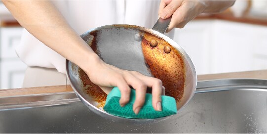 Scrub Dots Heavy Duty scrubs off burnt stains on stainless steel pan
